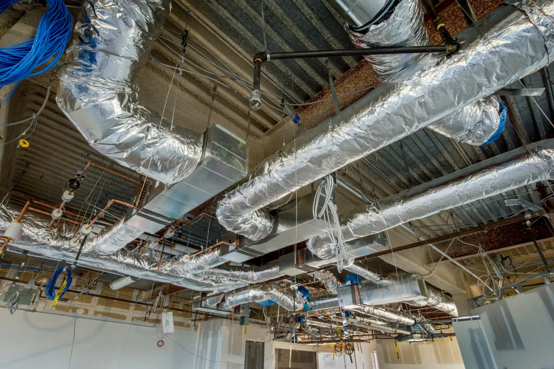 Exposed ductwork and pipes in building ceiling.